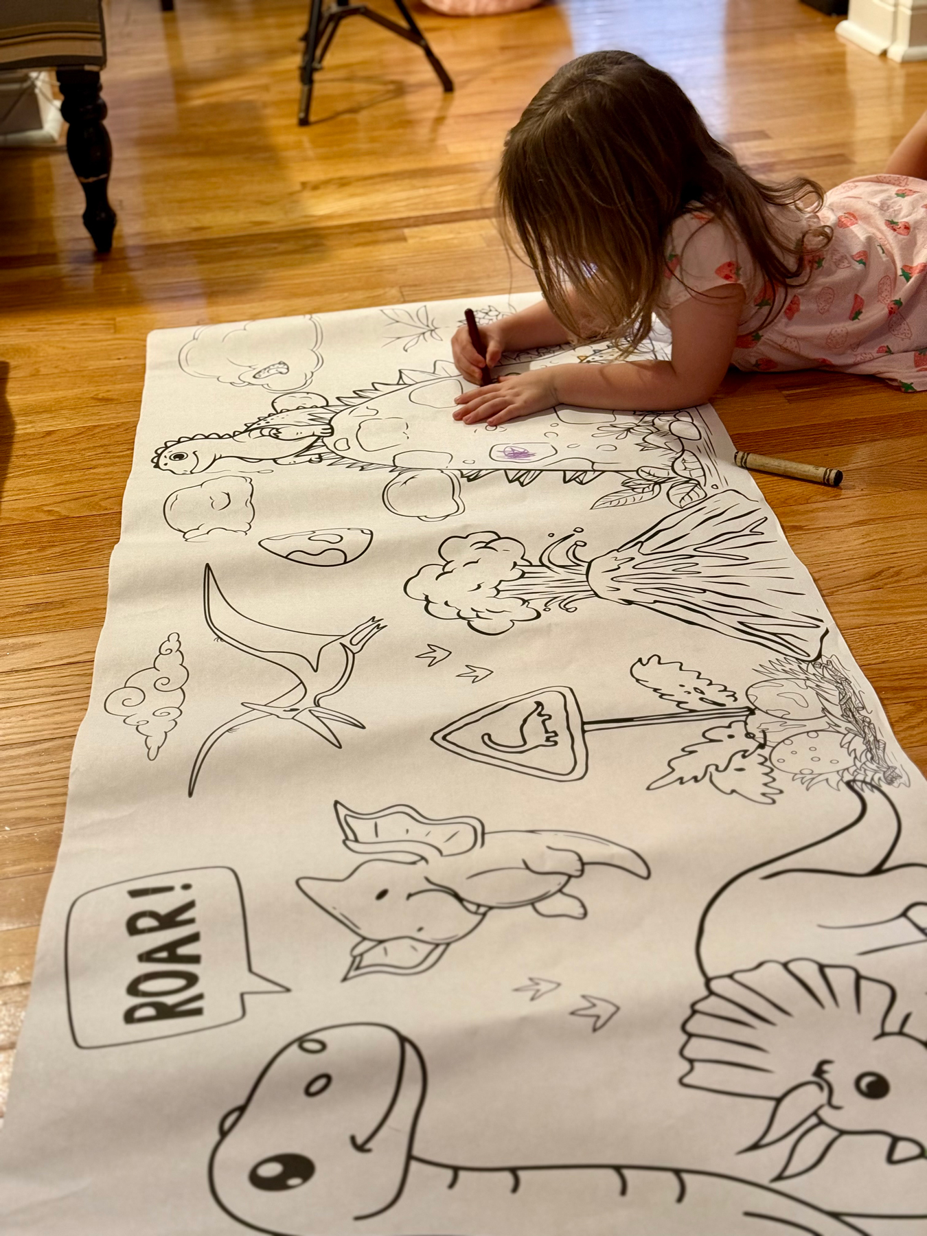 little girl coloring a large dinosaur themed banner