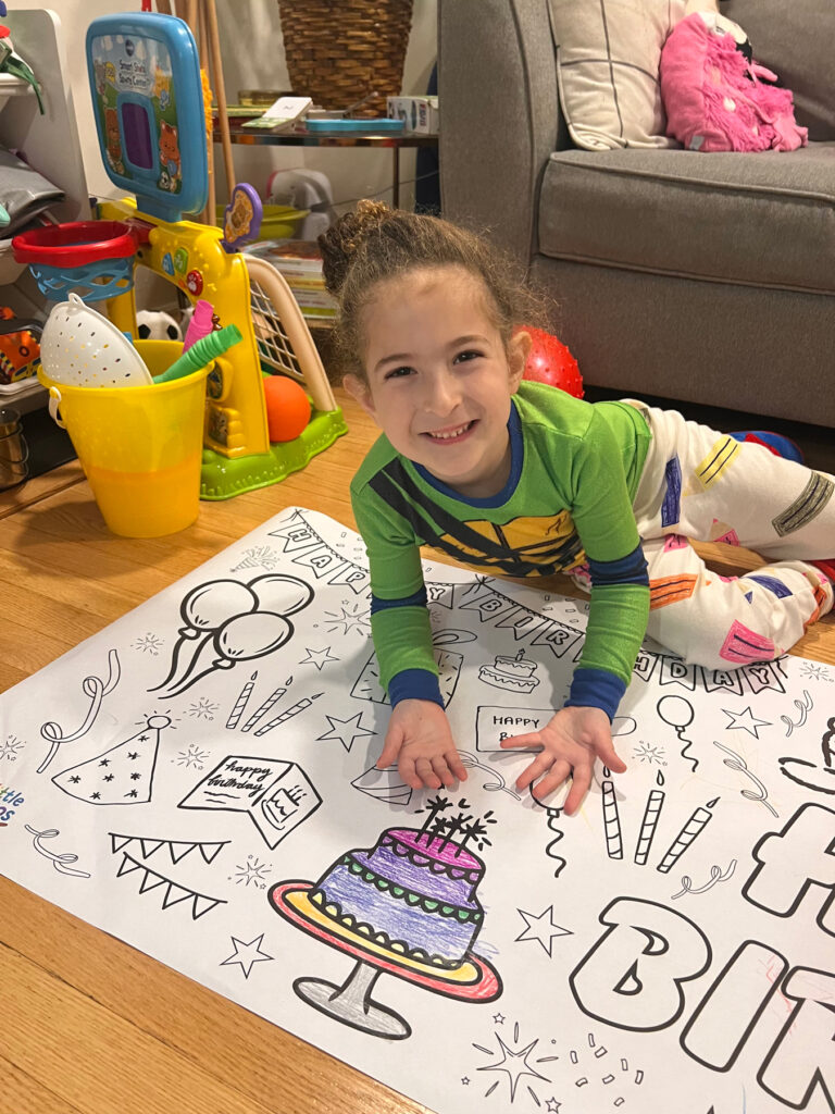 little girl on floor with giant birthday coloring banner