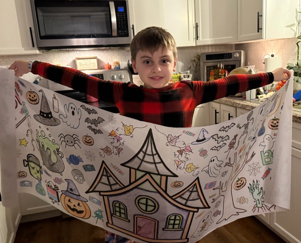 Young boy holding a halloween themed giant coloring banner